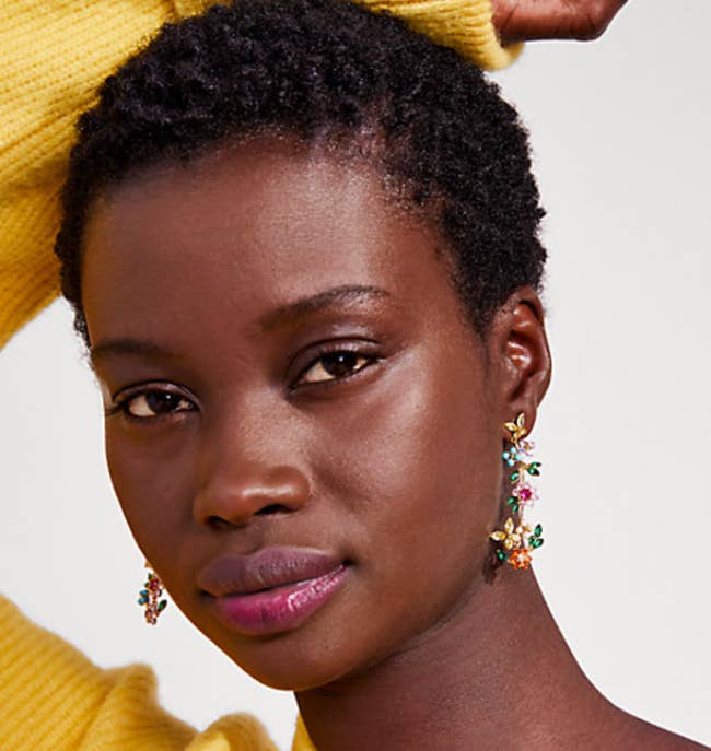 Model is wearing the dangle earrings that have various colors like light blue, green, pink, yellow, and orange on it