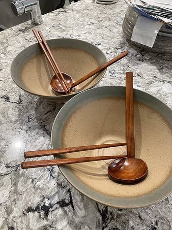 Two bowls with wooden chopsticks and bamboo spoon