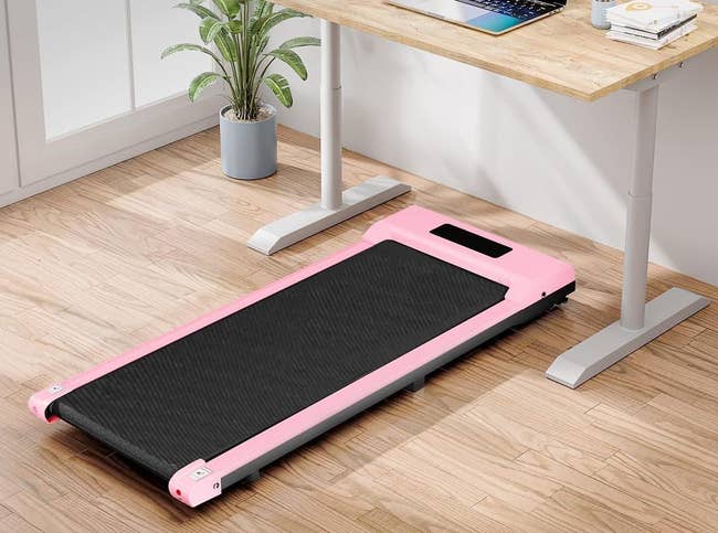 walking pad with pink trim under a standing desk
