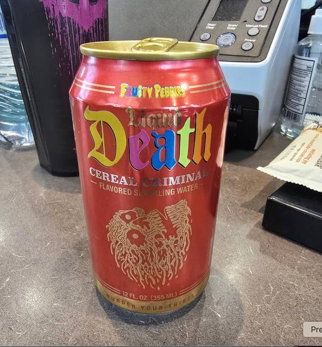 Liquid Death cereal-flavored sparkling h2o  tin  connected  a countertop, featuring bold branding and a playful skull illustration