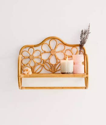 the mounted rattan daisy wall shelf with a candle and other decor on it