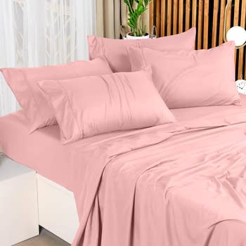 Bed with pink sheets and multiple pillows, suggesting comfortable bedroom textiles for shopping