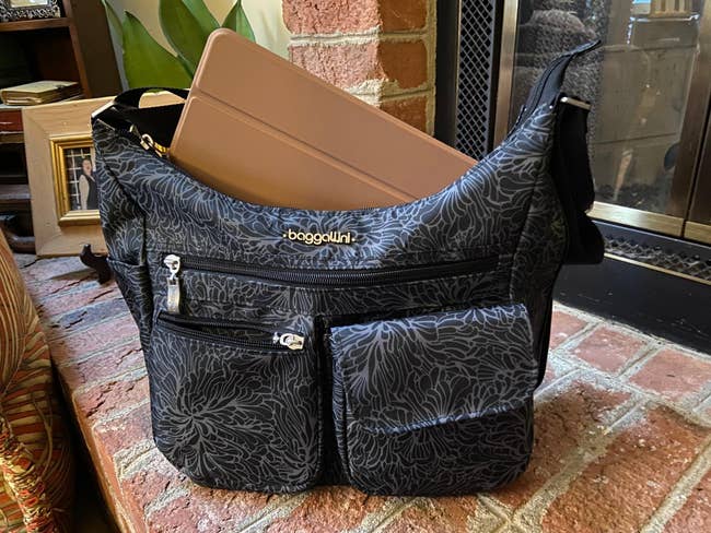 reviewer photo of a gray and black patterned purse with a lot of pockets