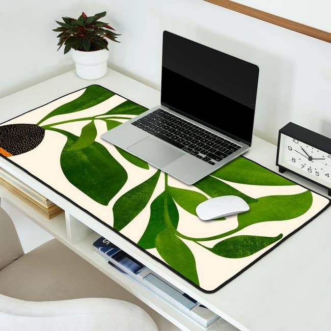  a desk mat with a plant illustration on it with a laptop sitting on top