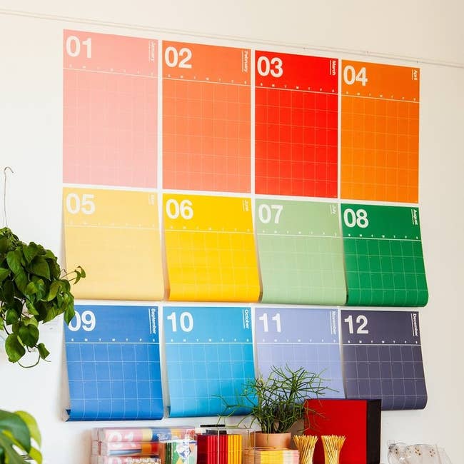 12 large calendar sheets each for a different month and each a different color on a wall