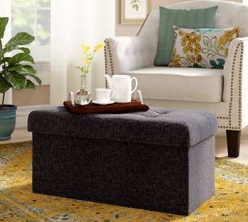 a black rectangular ottoman with a serving tray on top 