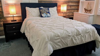 Reviewer image of white pleated full size comforter with matching pillow cases on a wooden bed frame and matching side tables