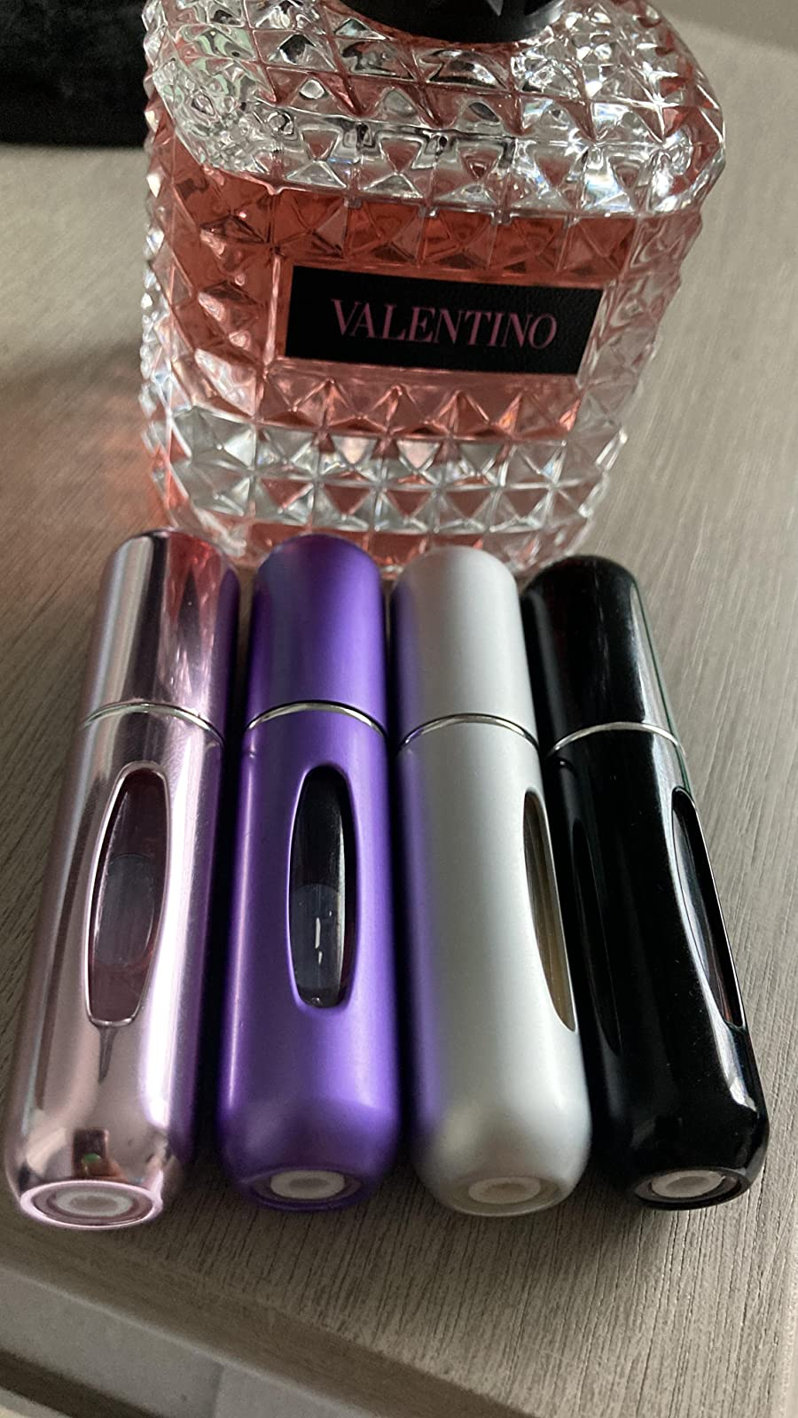 foto pengulas dari empat alat penyemprot parfum di depan botol parfum