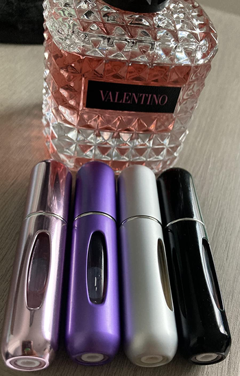 reviewer photo of the four perfume atomizers in front of a perfume bottle