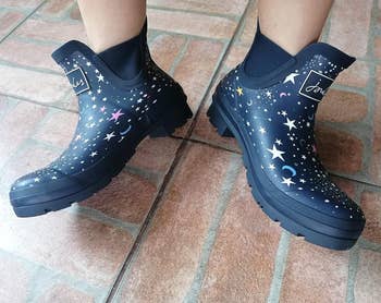 reviewer showing the black rain boots with stars on them