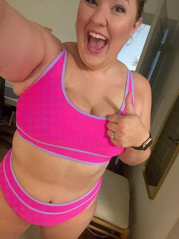 a reviewer wearing the two-piece set in pink featuring a checkerboard print and light purple trim 