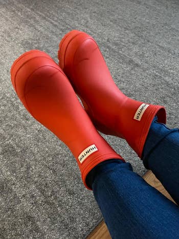 different reviewer wearing the short hunter rain boots in a reddish orange