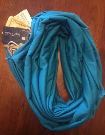 image of blue scarf with pocket open to reveal money, credit card, and keys inside 