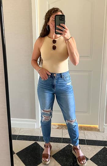 reviewer wearing the tan bodysuit with jeans