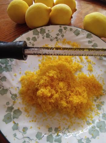 reviewer photo of a microplane over a plate of lemon zest, with a bunch of zested lemons above it