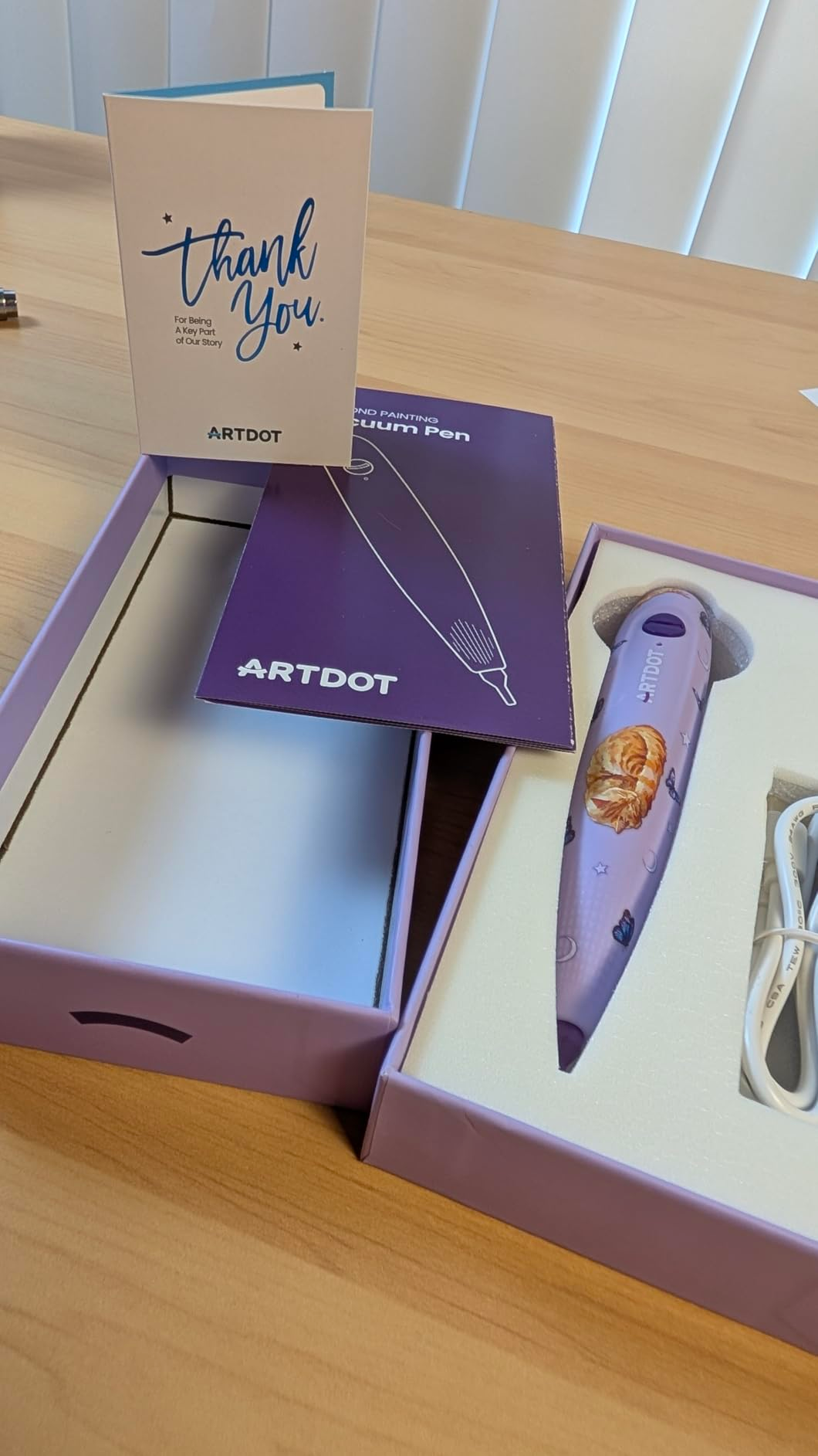 A purple ARTdot diamond coating  pen successful  packaging, alongside a thank-you enactment      and USB cablegram  connected  a woody  surface