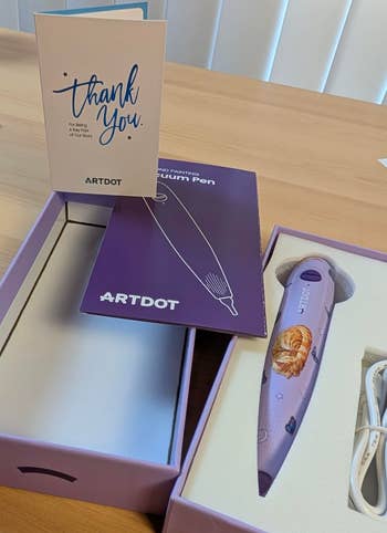 A purple ARTdot diamond coating pen successful packaging, alongside a thank-you enactment and USB cablegram connected a woody surface