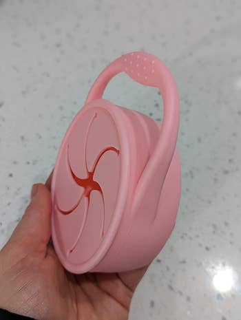 A reviewer holding a pink collapsible silicone s