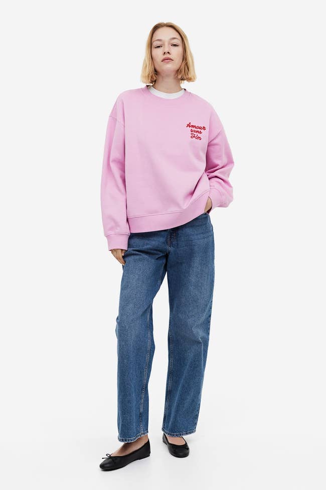 model wearing pink sweatshirt that says 