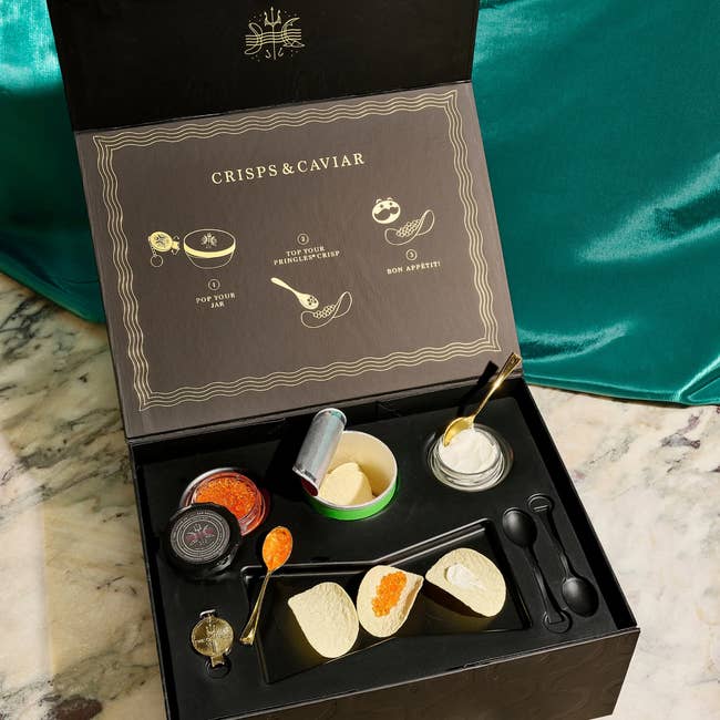 Luxury crisps and caviar set in an open box, with serving accessories, presented on a marble surface. Perfect for sophisticated gifting