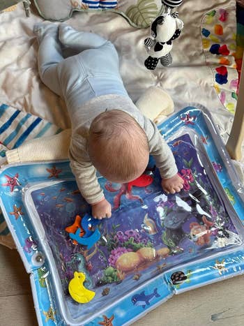 Infant playing on a water mat with floating toys