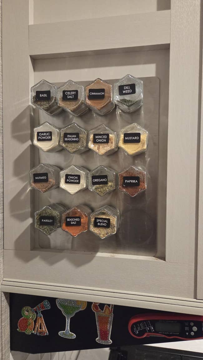 Magnetic spice rack connected a room furniture with labeled hexagonal containers, including basil, ail powder, and paprika