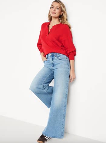 Person wearing a textured sweater and wide-leg jeans, leaning against a wall, showcasing casual benignant   for a buying  article
