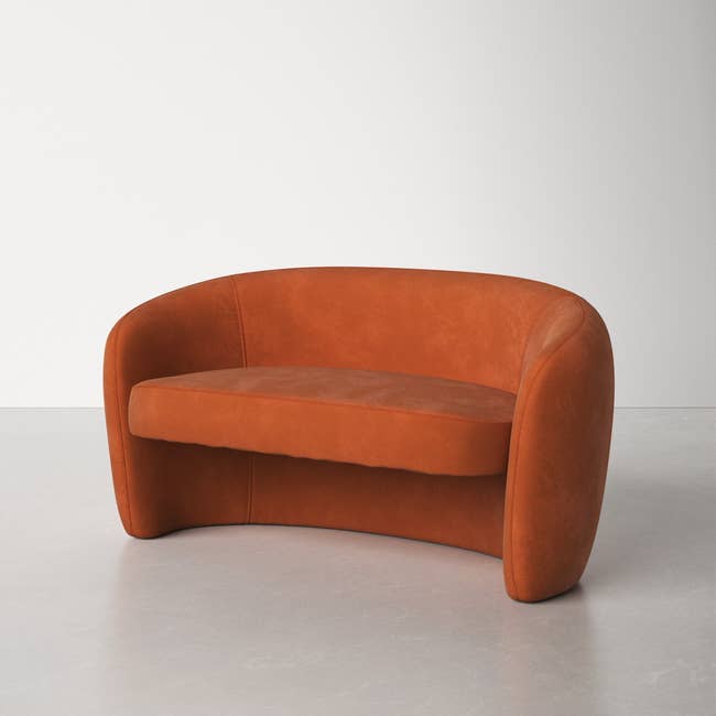 burnt orange organic shaped, curved couch with a floating platform seat