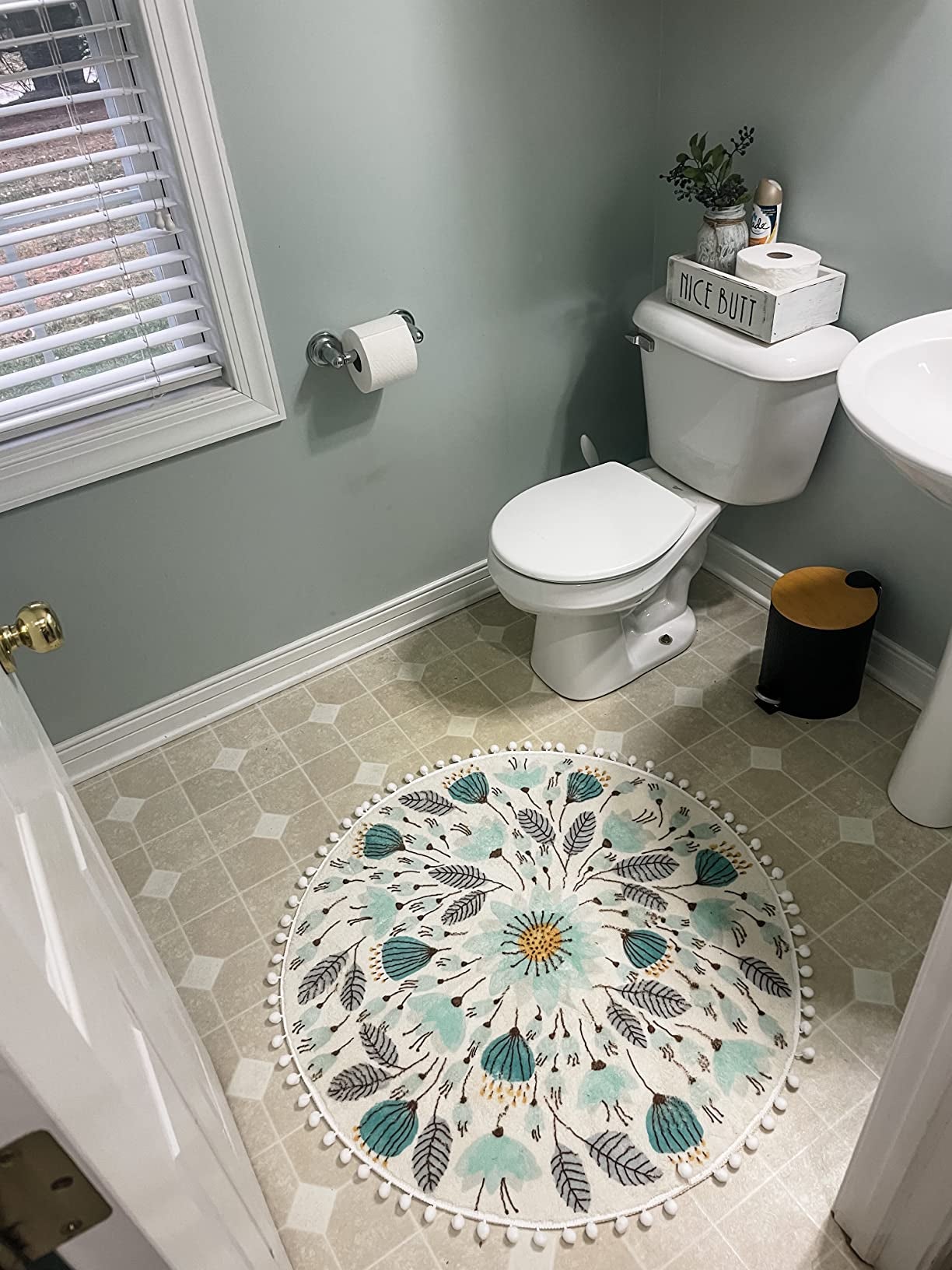 A circular rug with flowers and leaves on it, placed in a bathroom