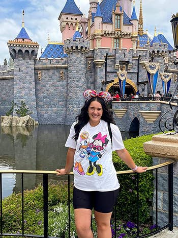 a reviewer at disney land wearing a white t-shirt with minnie mouse and daisy duck on it