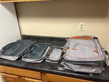 the three packing cubes laid side by side neck to backpack