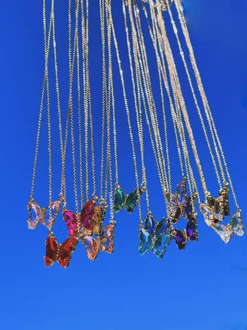 different colored butterfly necklaces dangling in air