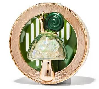 a car vent clip with a gold rim and a green snail sitting on a mushroom