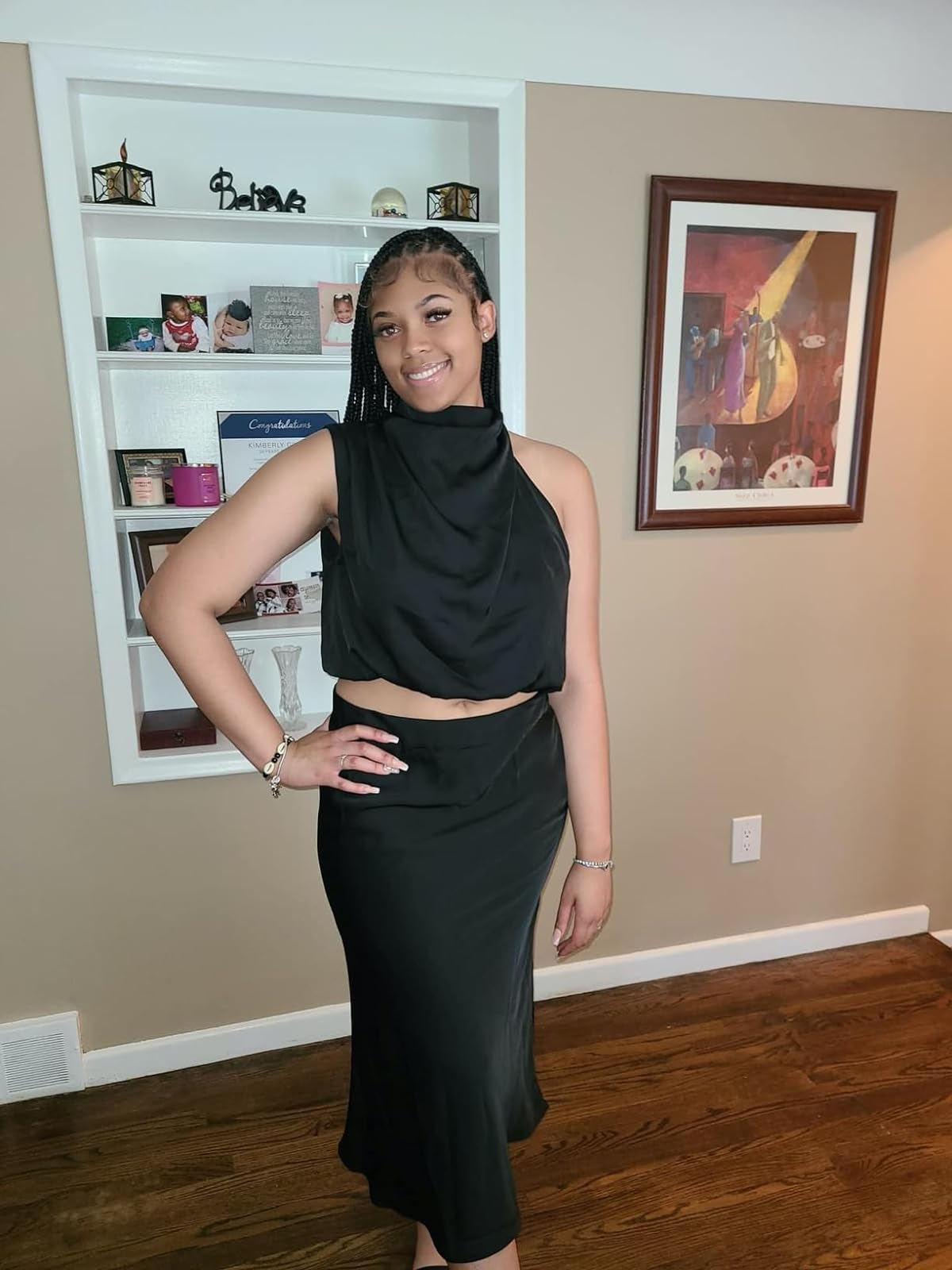 review in a black halter-neck dress with cut-out details, ready for an event. Jewelry includes bracelet and earrings