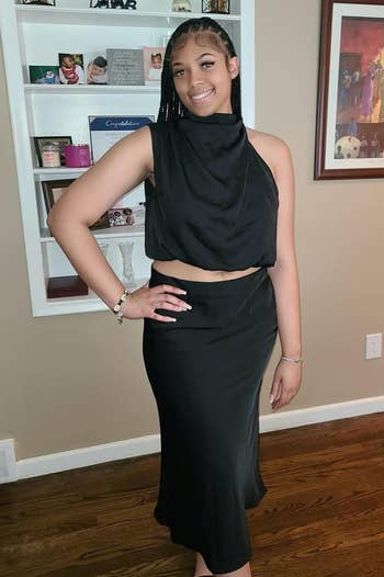 review in a black halter-neck dress with cut-out details, ready for an event. Jewelry includes bracelet and earrings