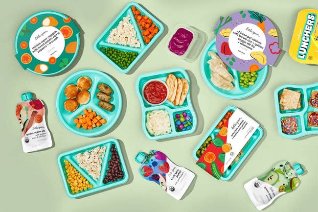 Assorted children's meal trays with healthy food options and squeezable fruit pouches arranged on a table