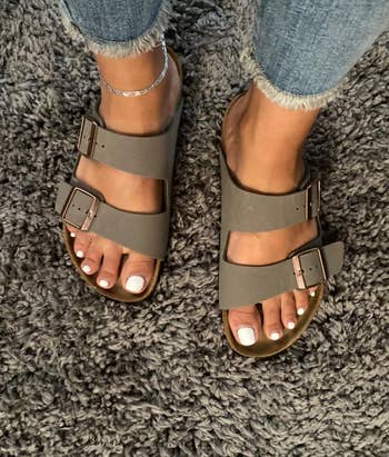 reviewer's feet wearing the dark gray sandals