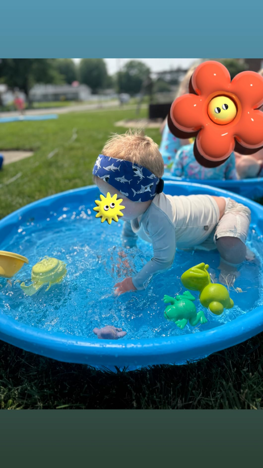 Reviewer's toddler wearing swimming headband with shark plan  and playing successful  pool