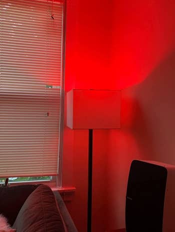 a reviewer photo of a lamp with a smart bulb inserted emitting red light 
