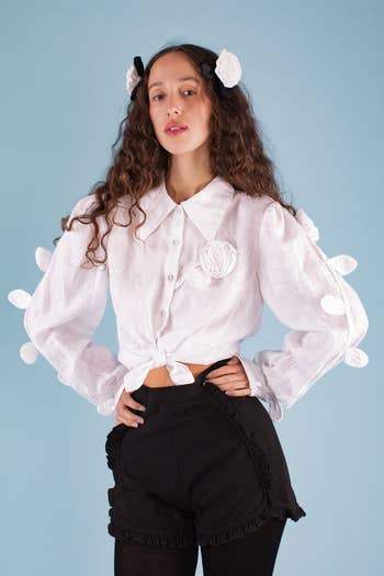model wearing a white blouse with flower appliqués