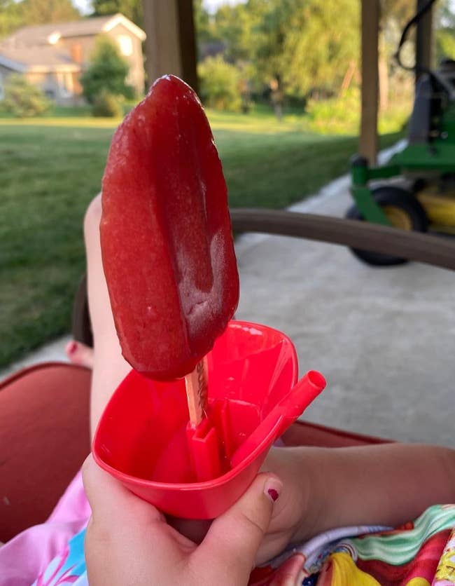 reviewer's child holding a popsicle using the red holder with clean hands