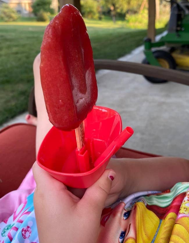 reviewer's child holding an ice pop using the red holder with clean hands