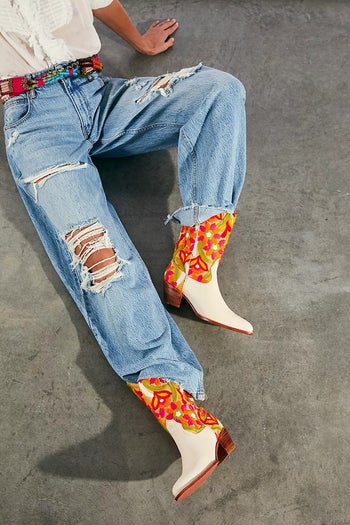 Model wearing cream boots with red, orange, yellow and green embroidery
