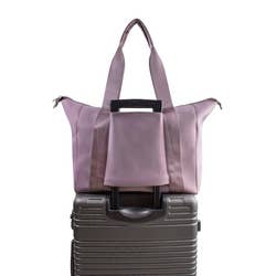 the lilac bag attached to a rolling suitcase via zippered handle slot