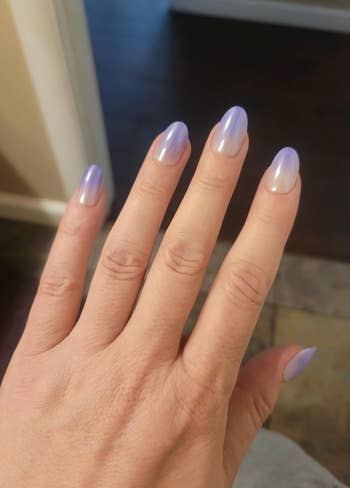 Manicured manus  with glossy, purple ombré nails showcasing a stylish gradient design