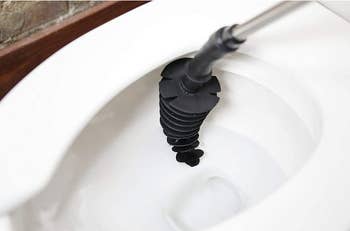 the black conical toilet plunger curving against the side of a toilet bowl