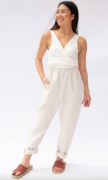 model in a white top and linen pants smiling and walking forward