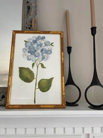 A framed coating  of bluish  hydrangeas with greenish  leaves is displayed with framework  