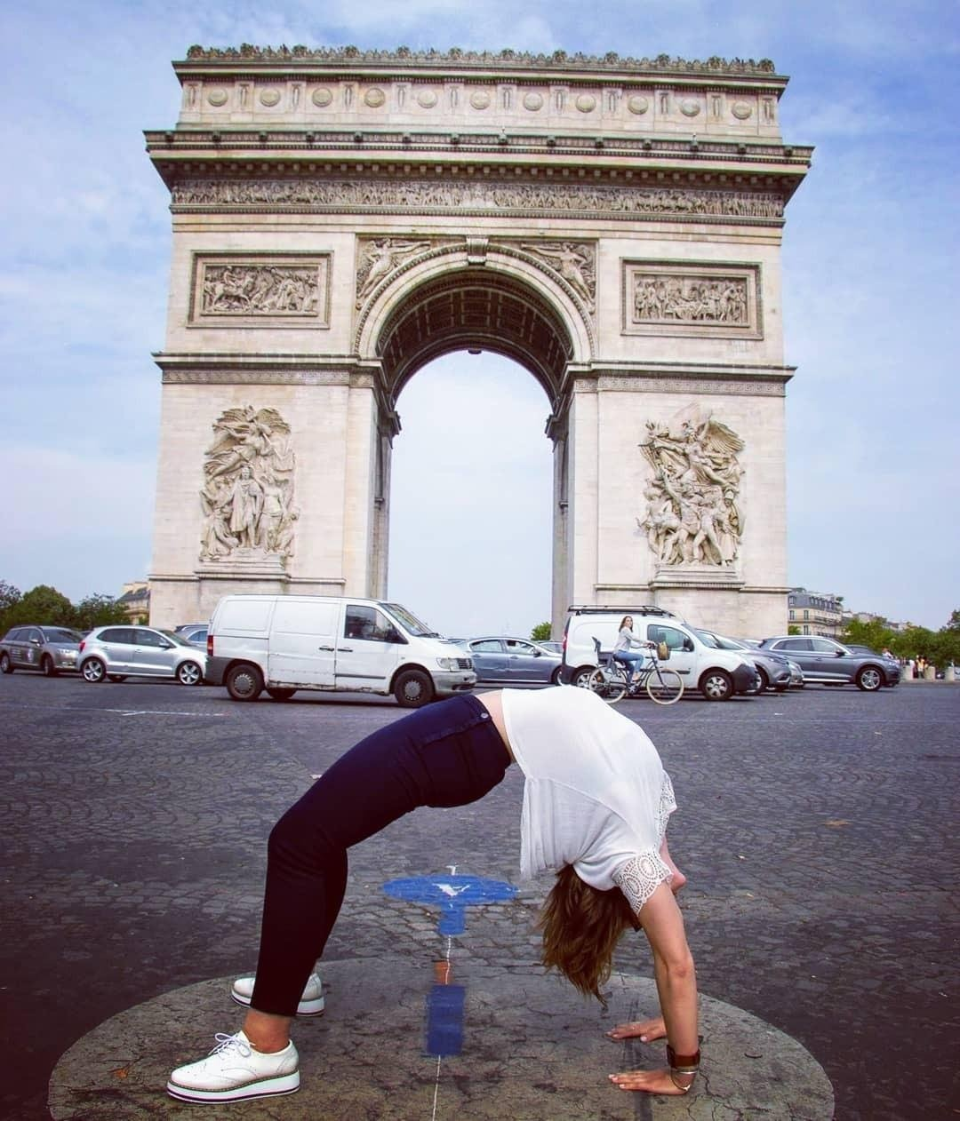 Person doing a backbend successful  beforehand   of the Arc de Triomphe, wearing casual attire with sneakers