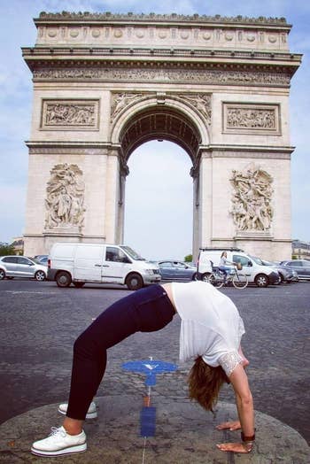 Person doing a backbend successful beforehand of the Arc de Triomphe, wearing casual attire with sneakers